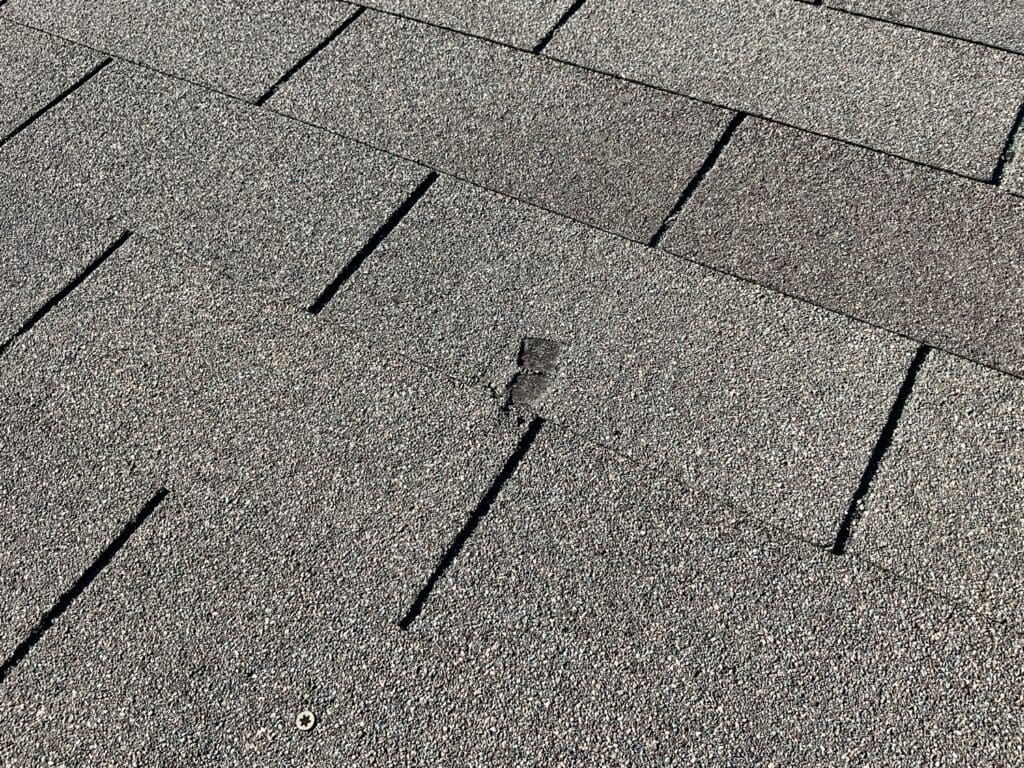 Damaged shingle on the roof of a brand new home, found during a new construction inspection