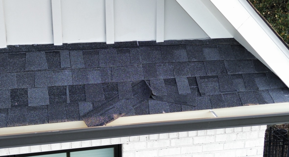 Unsecured shingles at the roof edge of a new construction home, found during a home inspection