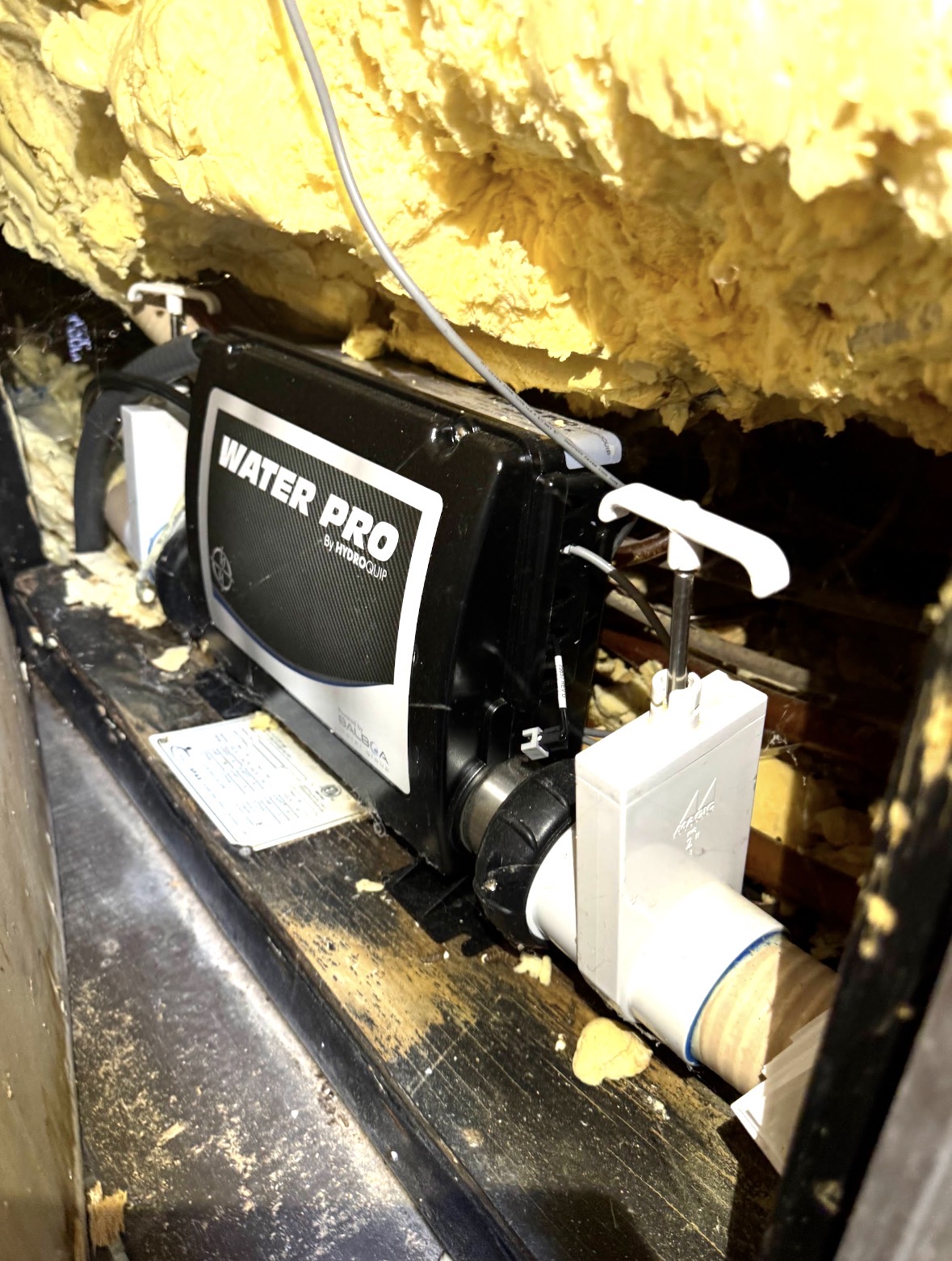 Spa heater and control pack under a hot tub cabinet, checked during a spa inspection
